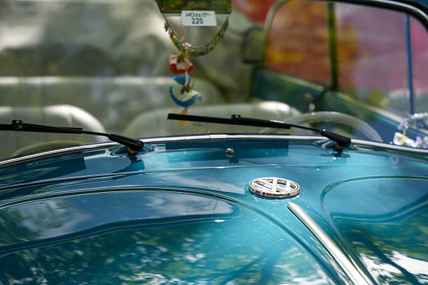 Germany Berlin May 11, 2025. VW emblem on hood. Close-up of a VW logo on a turquoise hood with sun reflections. The car reflects the elegance and charm of the classic Volkswagen era.