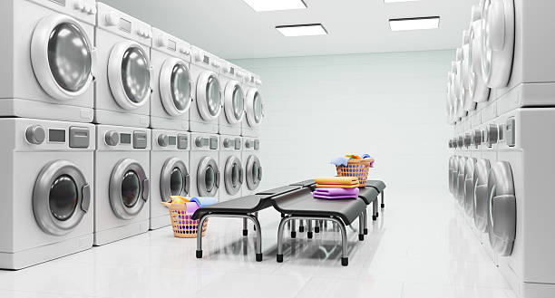 istock Public laundry room interior design. Self service laundromat with washer and dryer rows, waiting area with chairs, dirty clothes in basket and clean towels stack. Modern launderette 2215177629