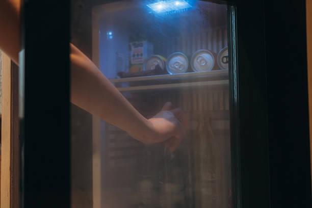 istock Close-up of a Hand Grabbing a Refreshing Bottle from a Mini Fridge. 2215179050
