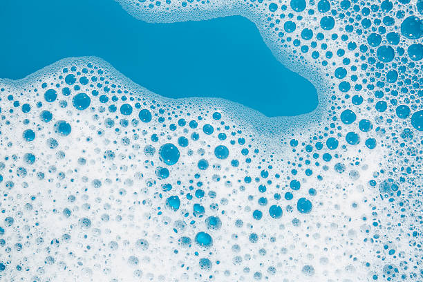 istock Detergent foam with bubbles on light blue background, top view 2215179928