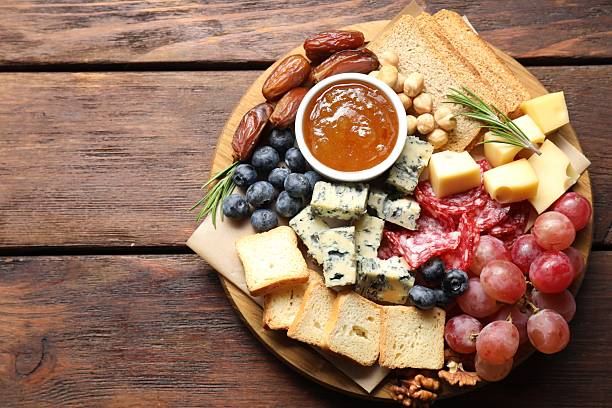 istock Different types of delicious cheese and other snacks on wooden table, top view. Space for text 2215180013