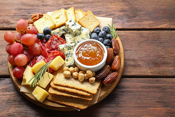 istock Different types of delicious cheese and other snacks on wooden table, above view. Space for text 2215180121