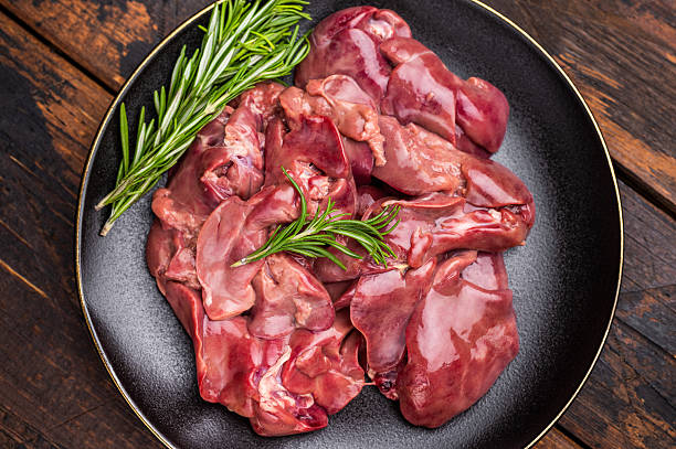 istock Raw chicken liver, featuring a glossy sheen and rich hue. A versatile ingredient that brings bold flavors to any culinary creation. wooden background. top view 2215180446