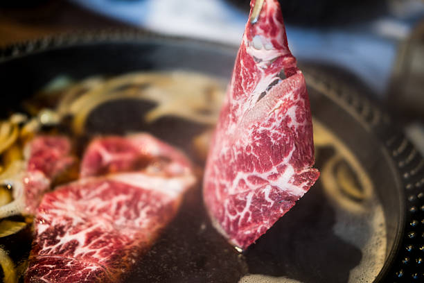Takes fresh beef raw sliced with marbled texture put cooking in hot boiled soup with vegetable Shabu Shabu or Sukiyaki