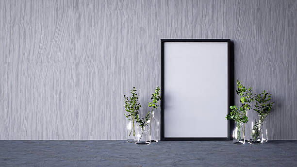 istock A minimalist setting featuring a blank frame against a textured wall, complemented by glass vases containing greenery. 2215181109