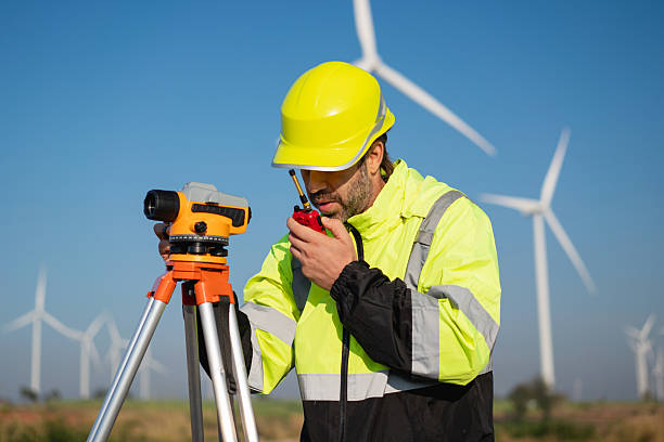 istock Surveying the land with high-precision tools, a field engineer works against a backdrop of wind turbines-where technology meets clean energy innovation. 2215181141