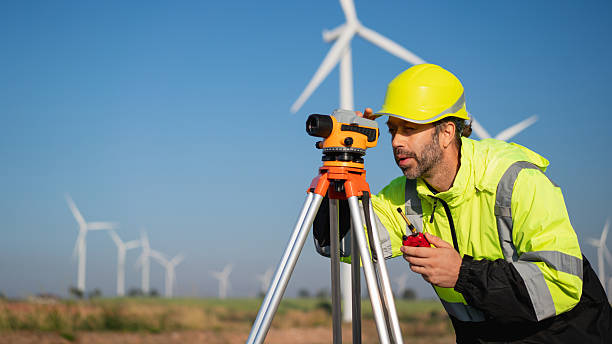 istock Surveying the land with high-precision tools, a field engineer works against a backdrop of wind turbines-where technology meets clean energy innovation. 2215181235