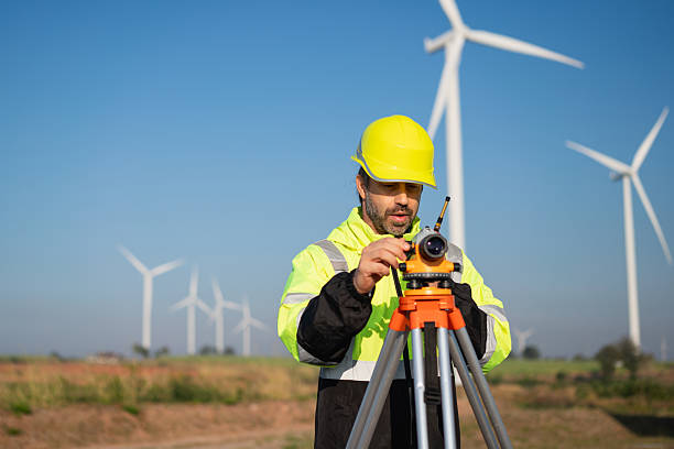 istock Surveying the land with high-precision tools, a field engineer works against a backdrop of wind turbines-where technology meets clean energy innovation. 2215181451