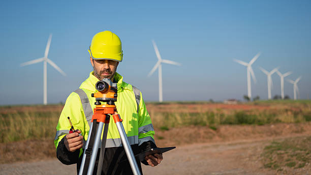 istock Surveying the land with high-precision tools, a field engineer works against a backdrop of wind turbines-where technology meets clean energy innovation. 2215181568