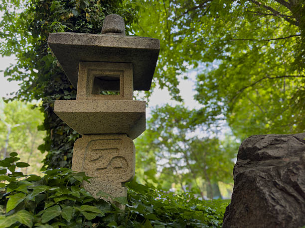 Stone lantern surrounded by lush green ivy and trees in a serene Japanese garden, creating a peaceful and natural atmosphere
