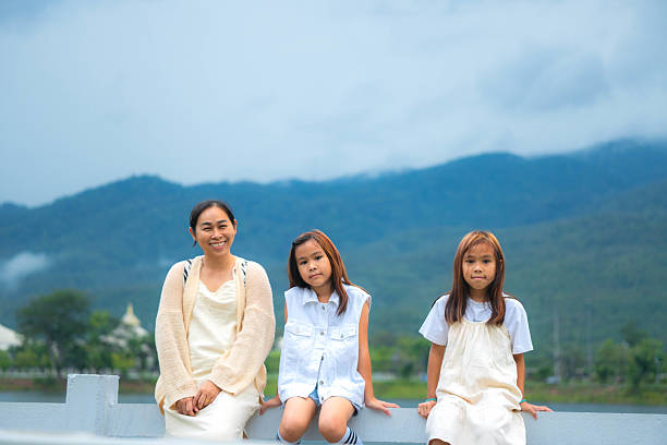 Family with three children posing together in a park, smiling and gesturing with their hands