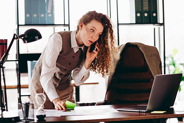 istock Young Businesswoman Speaking on the Phone and Analyzing Documents in an Office Workspace 2215190676