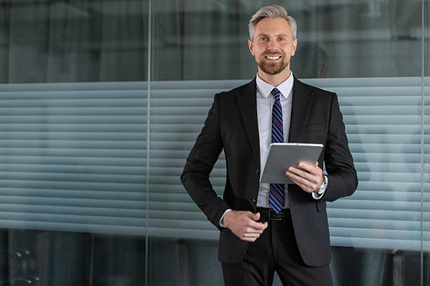 istock Smiling handsome businessman manager standing in office with tablet computer 2215190796