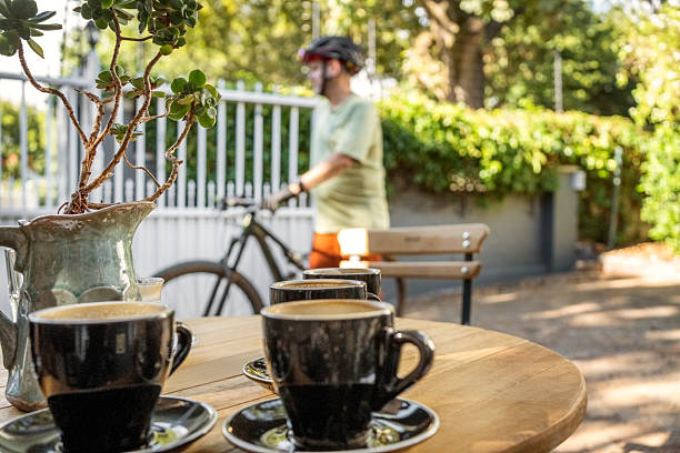 Cups of coffee on table with cyclist in background at cafe