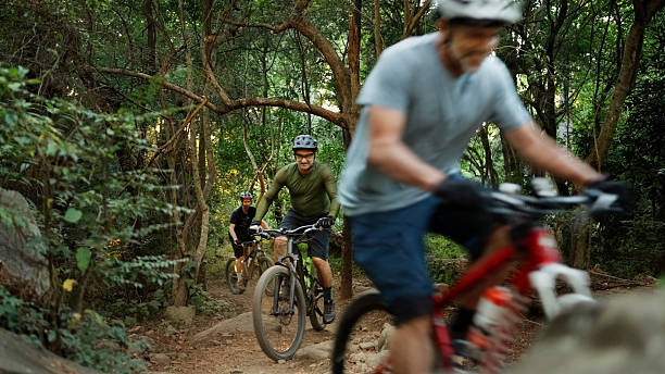 istock Mountain bikers cycling along a dirt trail in forest 2215191928