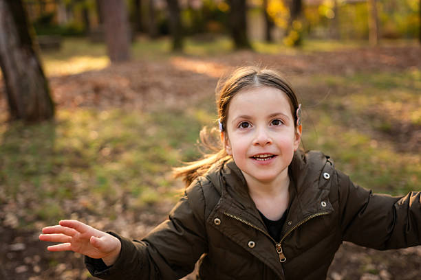 istock Girl looking up while playing in autumn park 2215192115
