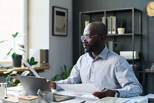 istock Black Businessman Looking through Graphs and Charts 2215193417