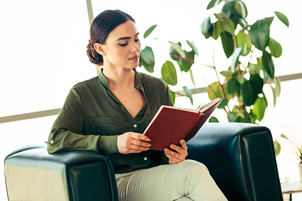 istock Confident businesswoman reading in a modern office environment surrounded by greenery 2215196336