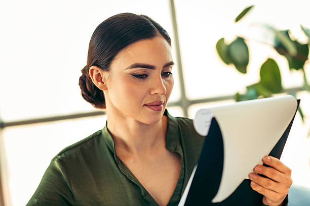 istock Confident professional businesswoman reading a document in a modern indoor workspace with natural light and elegant attire 2215196338