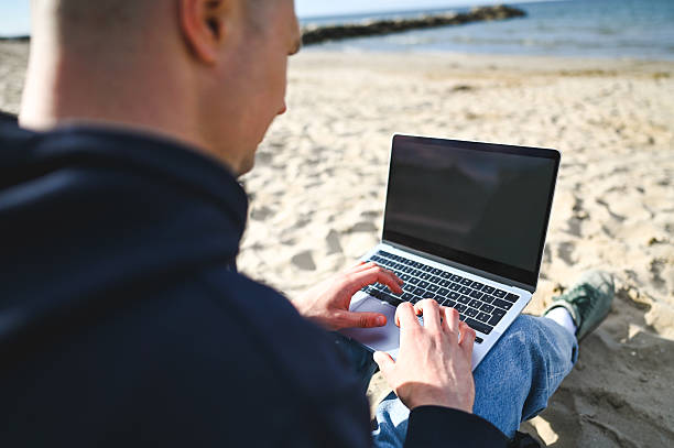 istock Freelancer working on laptop at the beach: enjoying remote work and vacation 2215198260