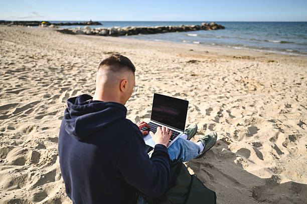 istock Freelancer working on laptop at the beach on sunny day 2215198261