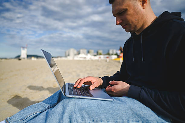 istock Freelancer working on laptop at the beach 2215198576