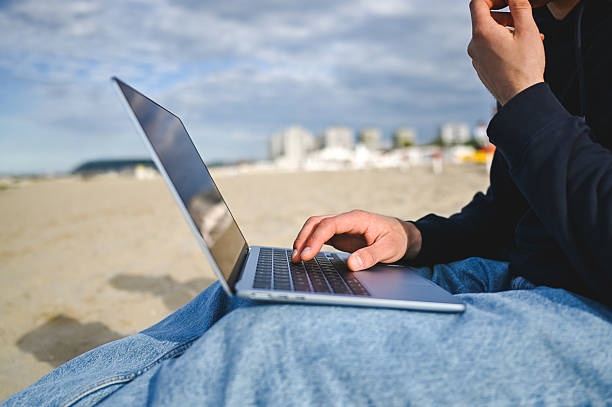 istock Freelancer working on laptop at the beach 2215198594
