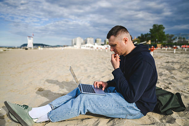 istock Freelancer working on laptop at beach enjoying remote work lifestyle 2215198601