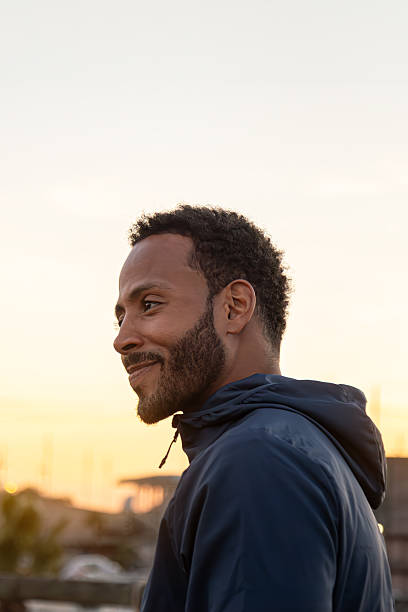 istock Young athletic man enjoying sunset on rooftop with urban view 2215204653