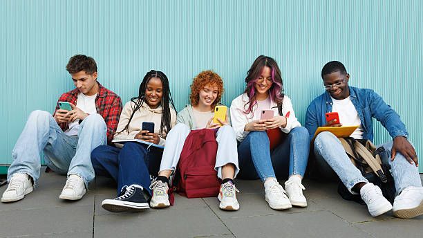 istock Students using smartphones sitting next to a turquoise wall 2215206948