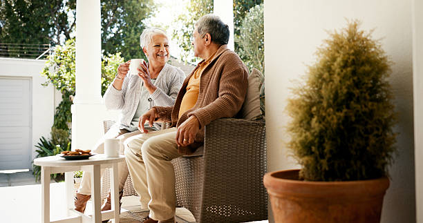 Bonding, talking and senior couple with coffee, home and elderly people with beverage for chat and morning. Happy, old man and mature woman with tea on patio, comfortable and family with cookies