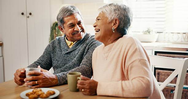 istock Kitchen, old couple and breakfast with coffee for laughing, bonding and biscuits with talking in retirement. Senior people, woman and man with smile for love, funny joke and cookies with tea at home 2215207096