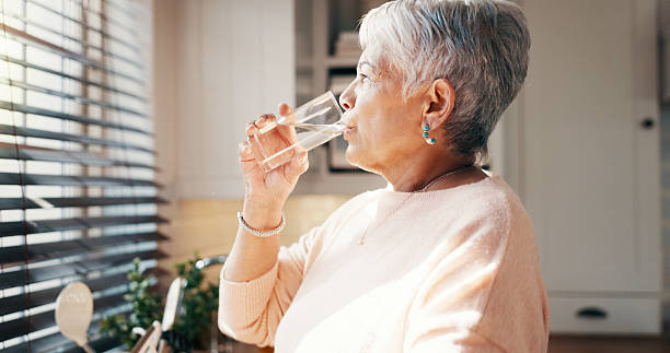 istock Thinking, senior woman and drink water for hydration, reflection and remember past life in kitchen. Elderly person, glass and refreshing beverage with thoughts, memory and future wellness at house 2215207142
