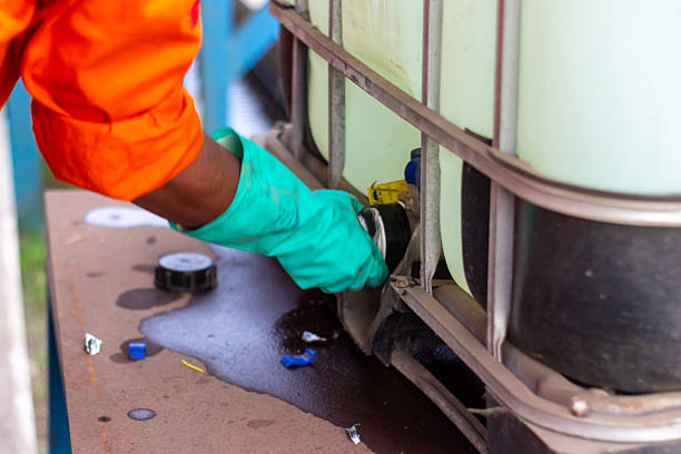 istock Green-gloved hand operates valve on industrial container with liquid spill. 2215208043