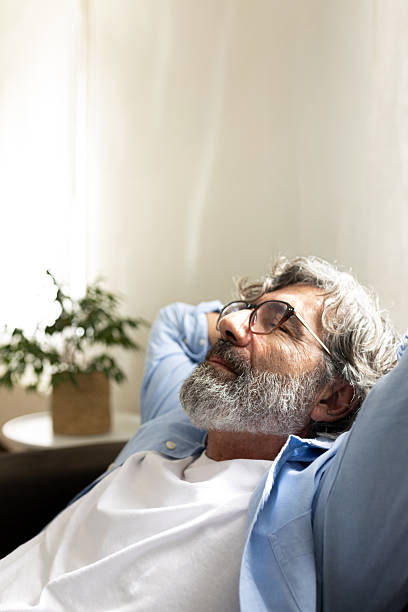 istock Senior man relaxing on sofa with hands behind head 2215209014