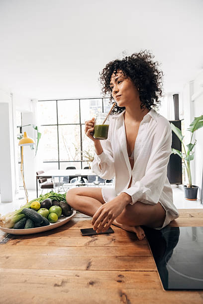 istock Young woman enjoying green smoothie in modern kitchen 2215210260
