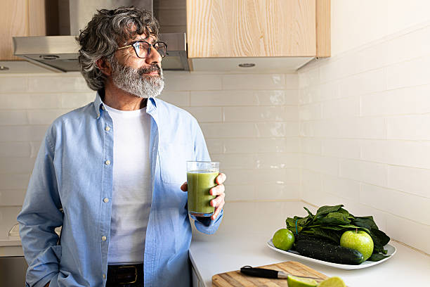 Senior man enjoying a healthy green smoothie in his kitchen