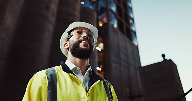 istock Man, engineer and thinking in city with smile for urban expansion, construction and low angle by building. Person, architect and perspective in street, town and infrastructure inspection 2215212213