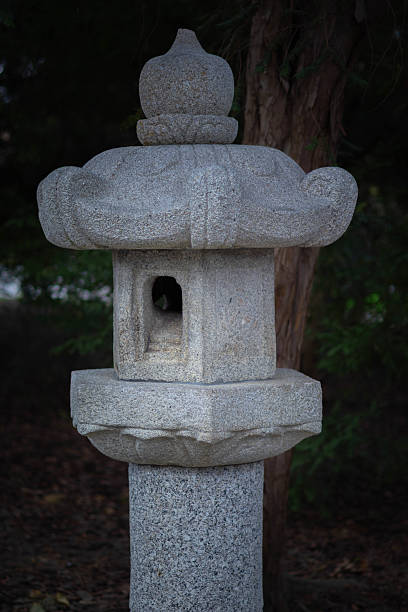 A traditional stone lantern stands amidst greenery in a quiet garden.