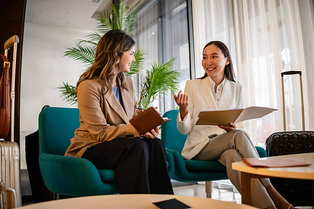 istock Businesswomen discussing travel plans in a luxury hotel lobby while using technology 2215229745