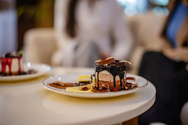 Variety of gourmet desserts beautifully arranged on white plates and glasses, served on a glass top wicker table in an inviting outdoor setting
