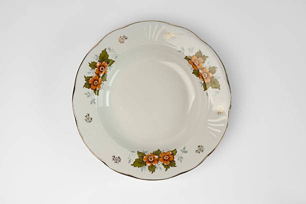 Empty vintage white plate with flowers in plate, isolated on white background. Looking down at a traditional, elegant, white with colorful flower print dinner plate.