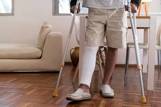istock Man walking with crutches and broken leg in cast at home 2215234744
