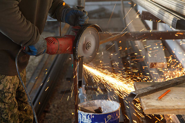 A man is using a power tool to cut metal. The sparks from the cutting process are flying everywhere