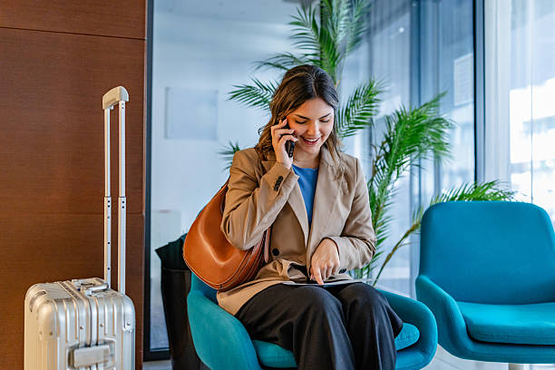 istock Young businesswoman making a reservation in a luxury hotel lobby while smiling and using her phone 2215241366
