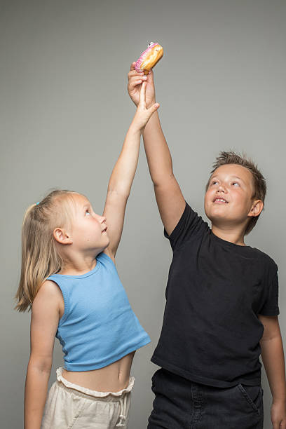 Playful blond little girl and boy standing outdoors, portrait.