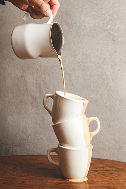 istock Brewing Macchiato With Stacked Espresso Cups Filled by Pouring Whipped Milk From Pitcher 2215252363