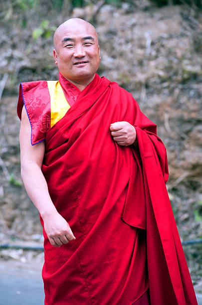 Monk walking to temple, Wangdue Phodrang Dzong, Punakha, Bhutan. The Royal Buddhist Kingdom of Bhutan, mountainous country in the Himalayas known for its monasteries, fortresses (or dzongs) and dramatic landscapes, ranging from subtropical plains to steep mountains and valleys, all of which are popular trekking destinations. Most famous landmark is Paro Taktsang monastery or Tiger’s Nest, clinging to precipitous cliffs above Paro Valley. Its Capital is Thimphu