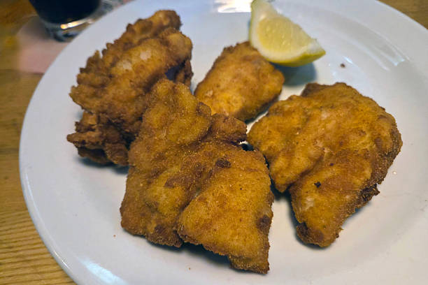istock Crispy Fried Chicken Pieces with Lemon Garnish on White Plate 2215260092