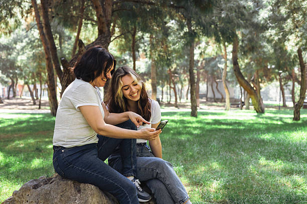 istock Friends enjoying a sunny day in the park while taking selfies with a smartphone 2215260496